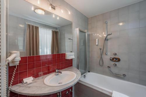 a bathroom with a sink and a tub and a shower at Hotel Eller in Solda