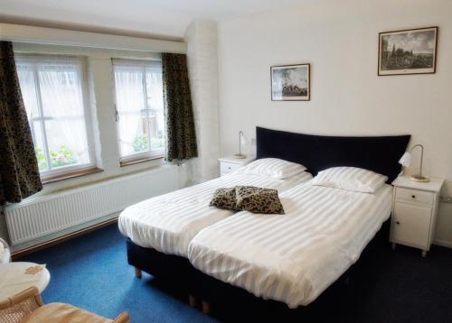 a bedroom with a large bed with white sheets and windows at Hotel De Oude Brouwerij in Mechelen