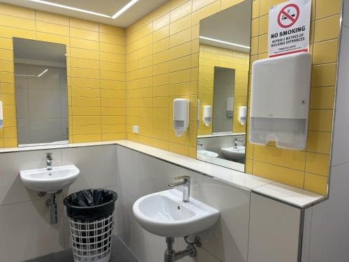 a public bathroom with two sinks and two mirrors at Global Backpackers Cairns in Cairns
