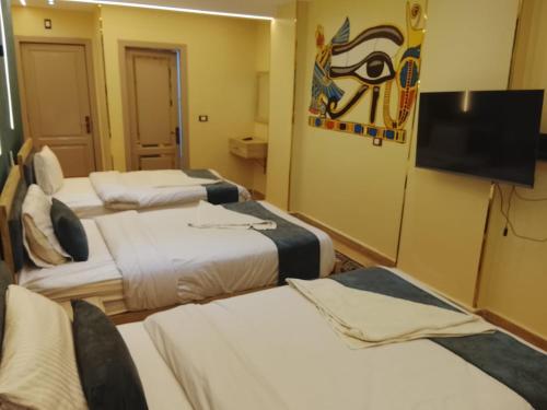 a room with three beds and a flat screen tv at Red Pyramids Hotel in Cairo
