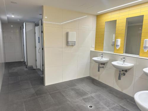 a bathroom with two sinks and two mirrors at Global Backpackers Cairns in Cairns
