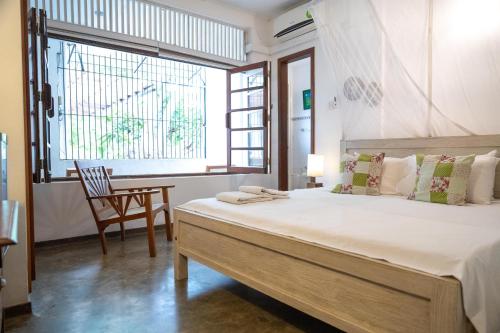 a bedroom with a large bed with a chair and a window at Colombo 07 Charming Home Stays in Colombo
