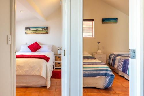 a bedroom with two beds and a doorway at Accessible Seaview Unit 3 in Waiheke Island