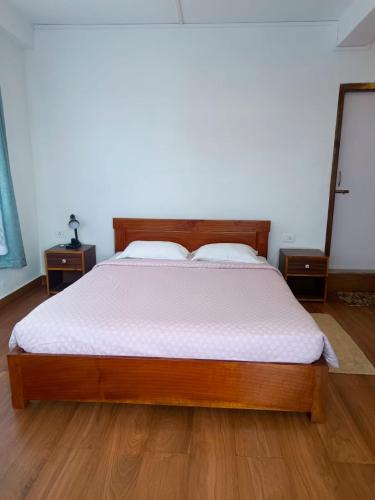 a bedroom with a wooden bed with a white mattress at Mawdong Homestay in Shillong
