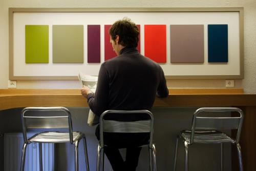 a man sitting at a counter in front of a painting at B&B HOTEL Bretigny-sur-Orge in Brétigny-sur-Orge