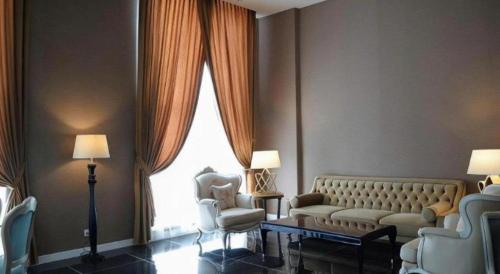a living room with a couch and two chairs and a window at Adimulia Hotel Medan in Medan