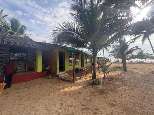 a house on the beach with palm trees next to it at Coco beach front stay in Gokarn