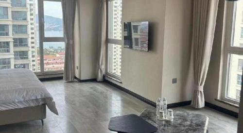 a bedroom with large windows and a bed and a table at GreenTree Inn Weihai Liugongdao Wharf Qingdao North Road Express Hotel in Weihai