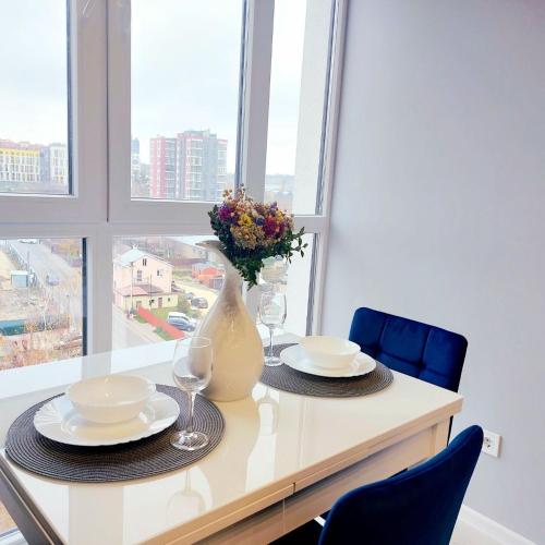 a table with plates and glasses and a vase with flowers at Зелена тераса in Lviv