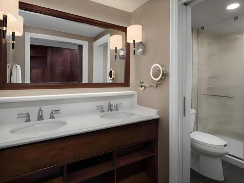 a bathroom with two sinks and a toilet and a mirror at Disney's Yacht Club Resort in Orlando