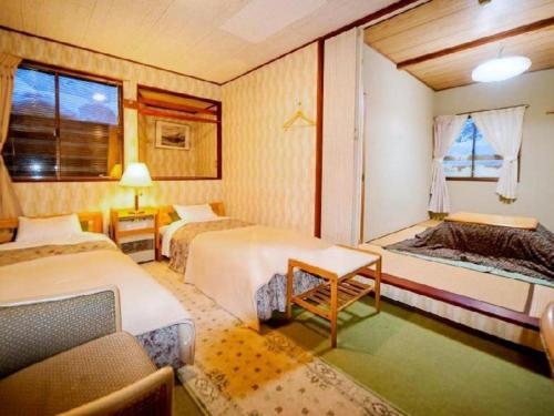 a hotel room with two beds and a window at Country Inn Canadian House in Myoko