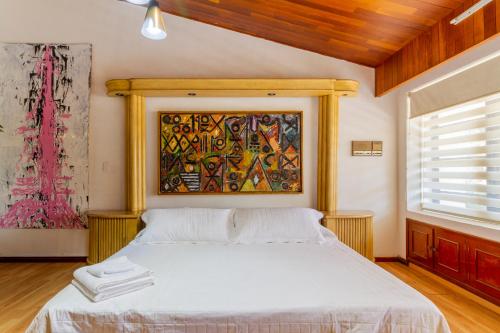 a bedroom with a bed with a painting on the wall at Chapalita Grand House in Guadalajara