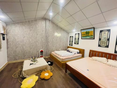 a room with two beds and a table in it at Nhà MIO in Khu Chi Lăng