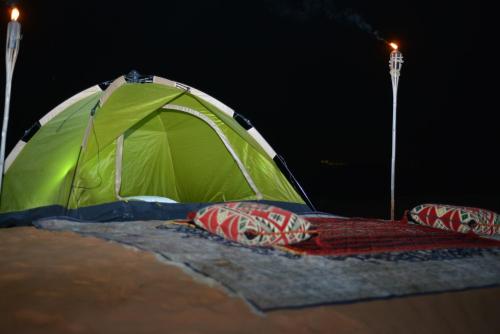 a green tent with two pillows in front of it at Bedouin Oasis Desert Camp- Ras Al Khaimah in Ras al Khaimah