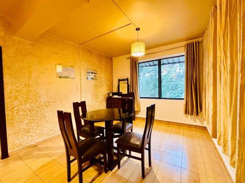 a dining room with a table and chairs and a window at Honeywood Holiday Homes in Mahabaleshwar