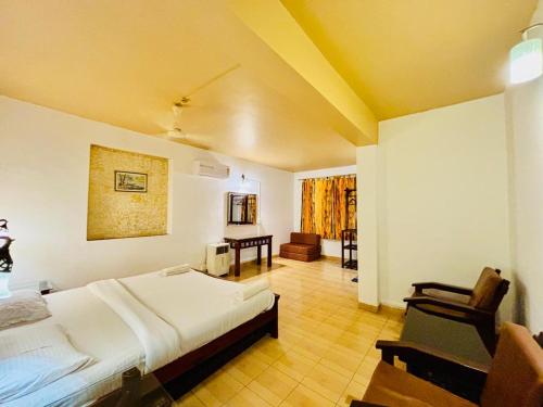 a bedroom with a bed and a chair in it at Honeywood Holiday Homes in Mahabaleshwar