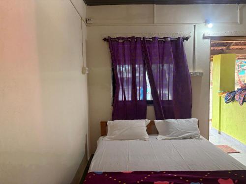 a bedroom with a bed with a purple curtain at Coco beach front stay in Gokarn