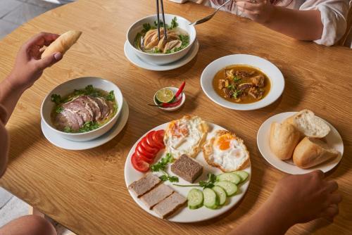 a wooden table with plates of food on it at J Village Hotel - Triệu Việt Vương in Hanoi