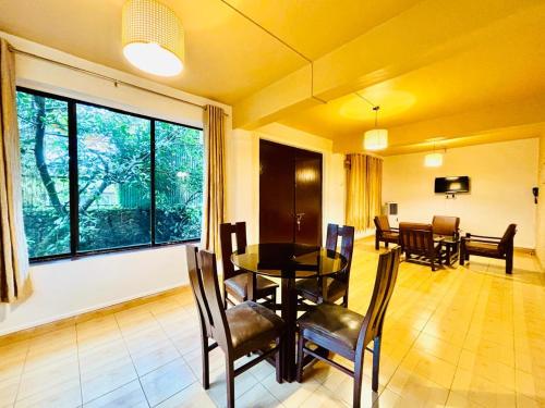 a dining room with a table and chairs and a large window at Honeywood Holiday Homes in Mahabaleshwar