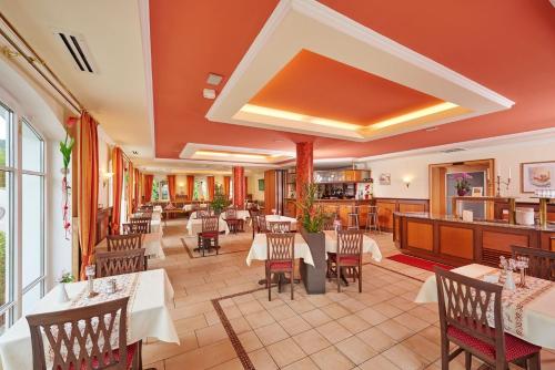 a restaurant with tables and chairs in a room at AKZENT Hotel Bayerwald-Residenz in Neukirchen