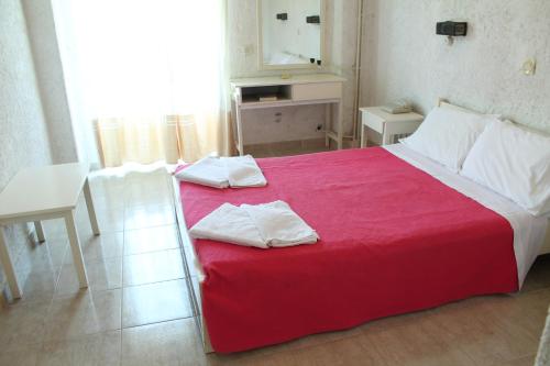 a bedroom with a red bed with two towels on it at Esperides Hotel in Myrtos