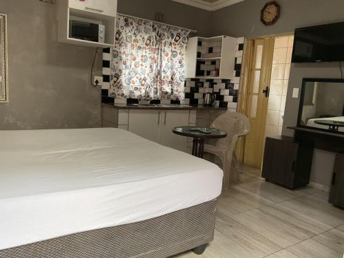 a bedroom with a bed and a table and a kitchen at northmead lodge in Benoni