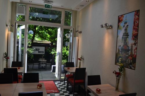 a restaurant with tables and chairs and a large window at Alp Hotel in Amsterdam