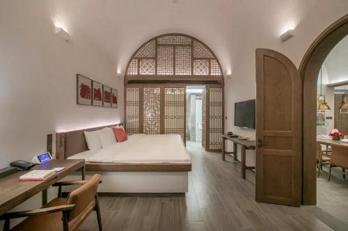 a bedroom with a bed and a desk and a kitchen at Wanda Realm Yan'an in Yan'an