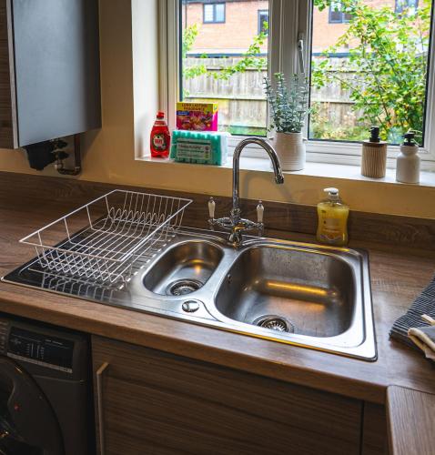 a kitchen sink with a drying rack above it at Sherbet House Stylish 3BR, 6 Guests Contractor Near NEC and Birmingham Airport Near NEC and Birmingham Airport in Water Orton