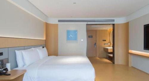 a bedroom with a large white bed and a bathroom at 7 Days Inn Zhangjiakou Chongli Yuxing Road in Zhangjiakou