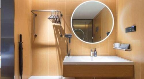 a bathroom with a sink and a mirror and a shower at 7 Days Inn Zhangjiakou Chongli Yuxing Road in Zhangjiakou