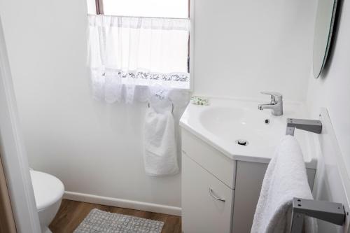 a white bathroom with a sink and a toilet at Matahari Apartments and Villas in Upper Hutt