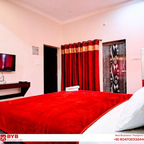 a bedroom with a red bed with a red curtain at BYB Boutique Hotel in Thanjāvūr