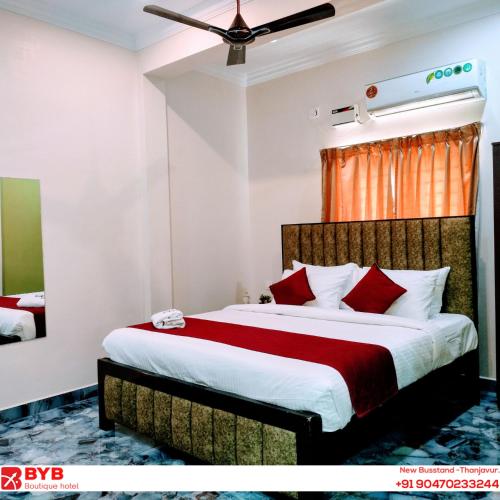 a bedroom with a large bed with red pillows at BYB Boutique Hotel in Thanjāvūr