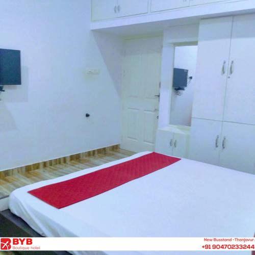 a bedroom with a white bed with a red blanket at BYB Boutique Hotel in Thanjāvūr