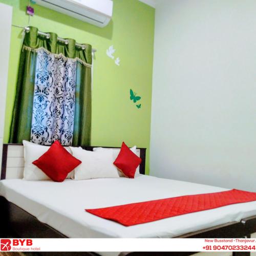 a bedroom with a bed with red and white pillows at BYB Boutique Hotel in Thanjāvūr