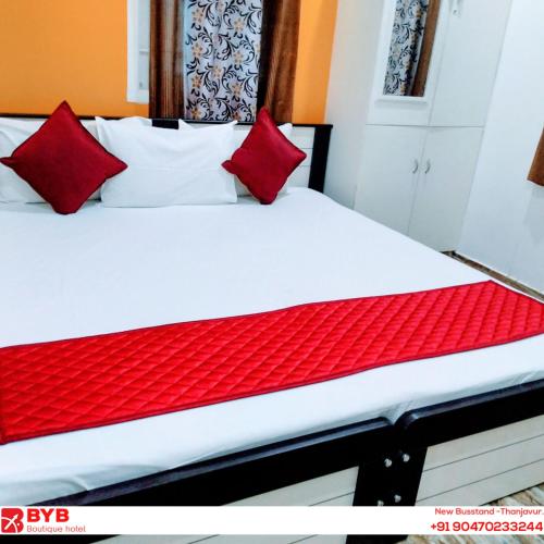 a bed with red and white pillows on it at BYB Boutique Hotel in Thanjāvūr