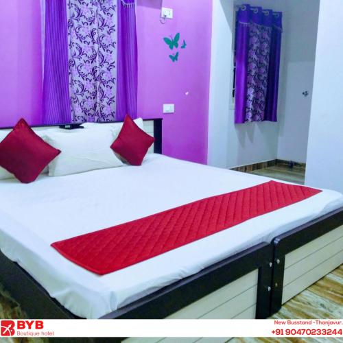 a bedroom with a bed with red pillows and purple curtains at BYB Boutique Hotel in Thanjāvūr
