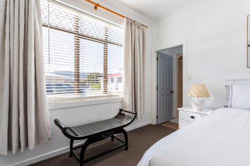 a bedroom with a bed and a chair in front of a window at Matahari Apartments and Villas in Upper Hutt