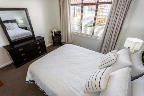 a bedroom with a white bed and a mirror at Matahari Apartments and Villas in Upper Hutt