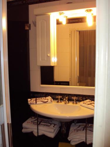 a bathroom with a sink and a mirror and towels at Hotel Rey in Buenos Aires