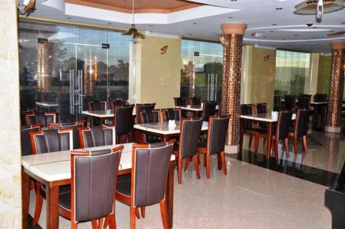 a dining room with tables and chairs and windows at Super Paradise Hotel in Kampala