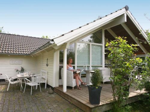 a woman sitting on the porch of a house at 6 person holiday home in Dronningmølle-By Traum in Gilleleje