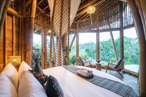 SelatにあるMagical Bamboo House with Breathtaking viewの大きな窓のある部屋のベッド
