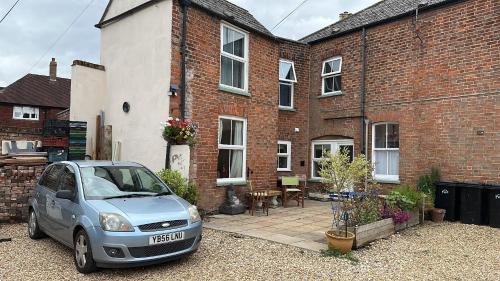 a small car parked in front of a brick house at The Mansion House Hotel in Holbeach