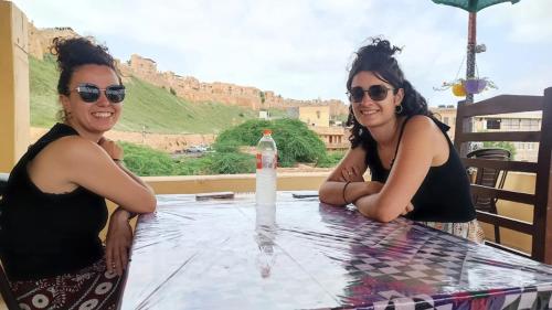 two women sitting at a table with a bottle of water at Relax Inn Jaisalmer in Jaisalmer