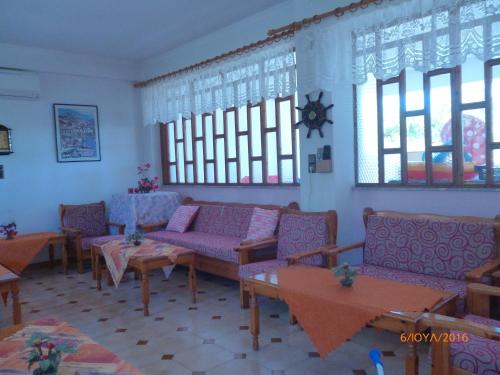 a living room with couches and tables and windows at Golden Sun Rooms in Pyrgi Thermis