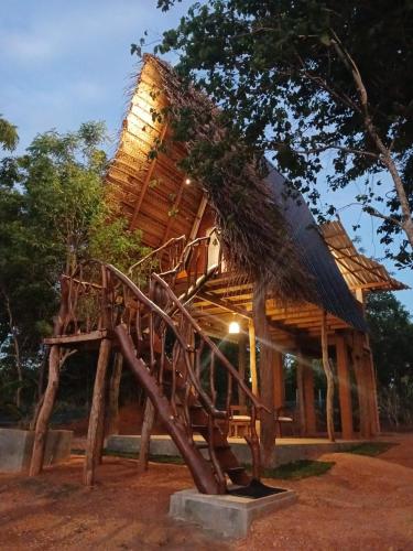 a tree house with a thatched roof at Chena Hut Habarana in Habarana