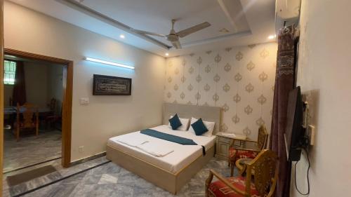 a bedroom with a bed and a table and a chair at Midways Guest House and Hotels in Islamabad