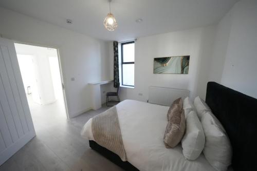a white bedroom with a bed with pillows at Ealing Broadway Great Stay 7-Minute Walk from the Underground in Ealing
